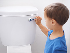 A young boy flushing a toilet after use.