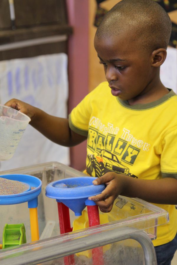 Young boy holding a measuring cup of water.