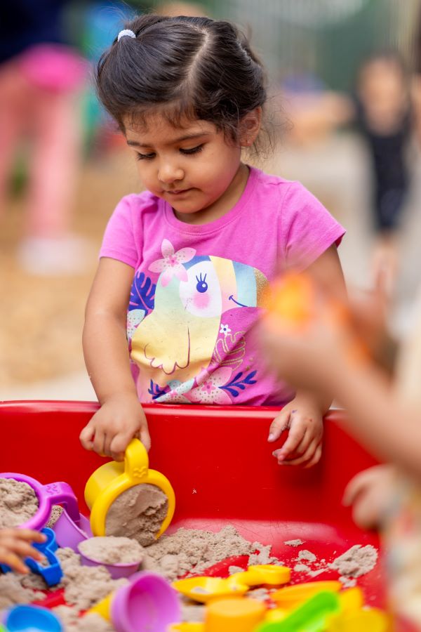 Young girl scooping up sand.