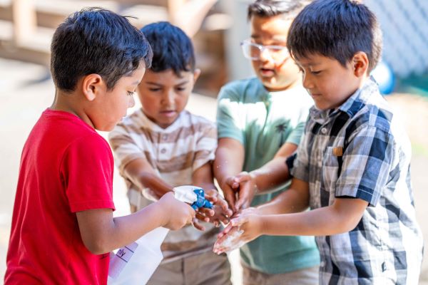 Boys using a squirt bottle to spray their hands after messy play.