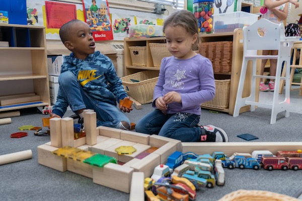 Un niño y una niña jugando con grandes bloques de madera.