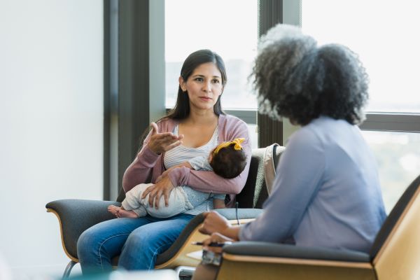 Teacher meeting with an specialists while having a baby in her arms.