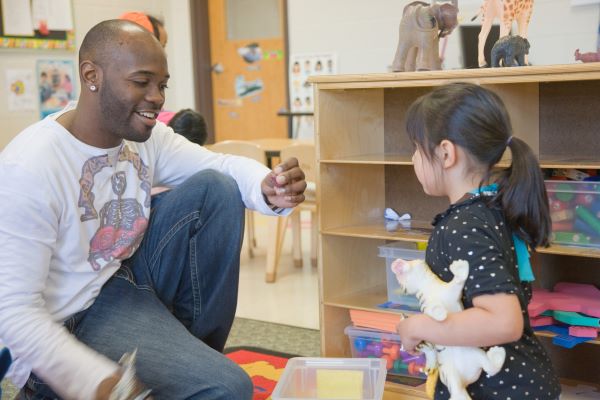 Teacher talking with a child in a classroom.