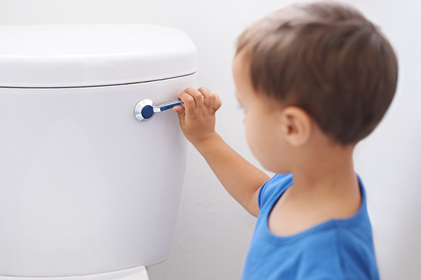 Young child flushing the toilet.