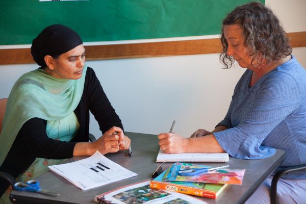 Two women at a desk going over notes.