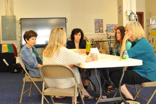 Five women gathered around a table sharing Information about emergency preparedness, response, and recovery.