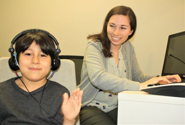 Child wearing headphones being administered a hearing test.